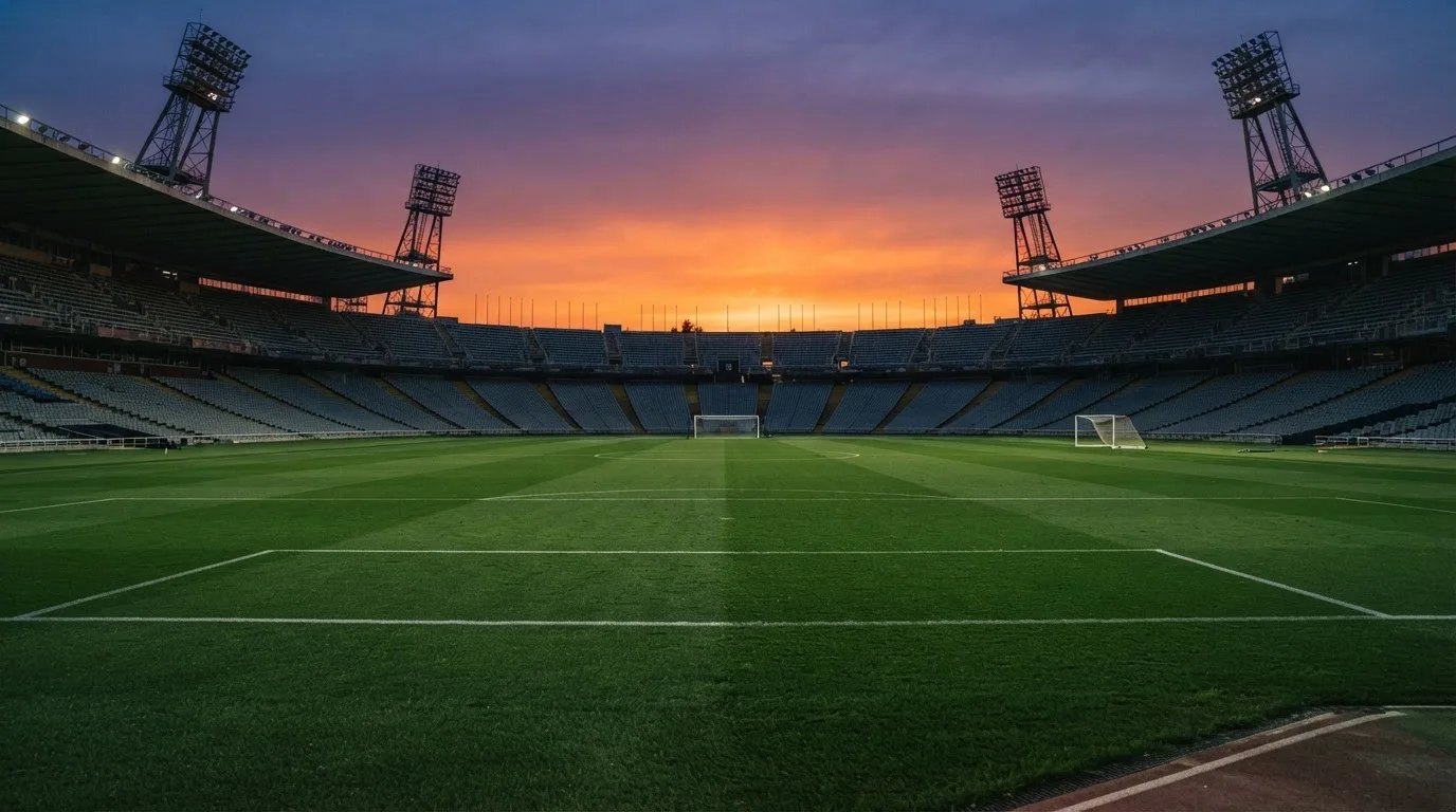 Un estadio de fútbol vacío con torres de iluminación al atardecer