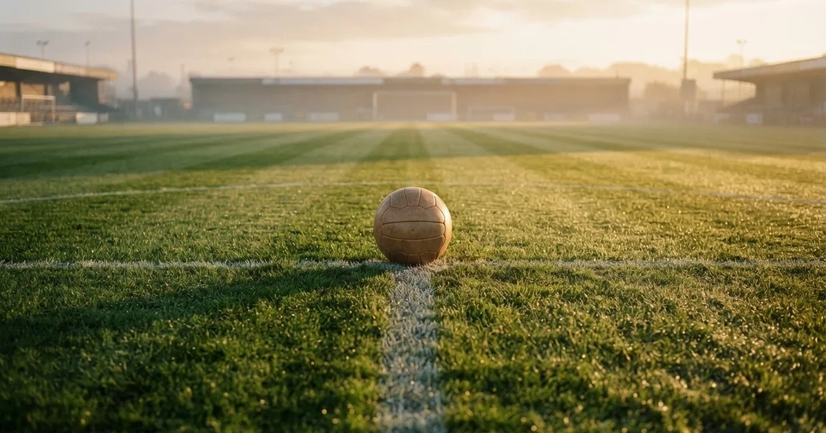 Un balón en el punto central de un campo de césped a la luz de la mañana