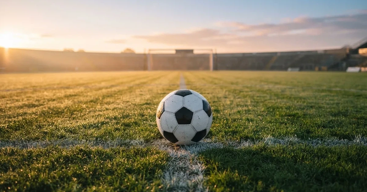 Un balón en el punto central de un campo de césped a la luz de la mañana