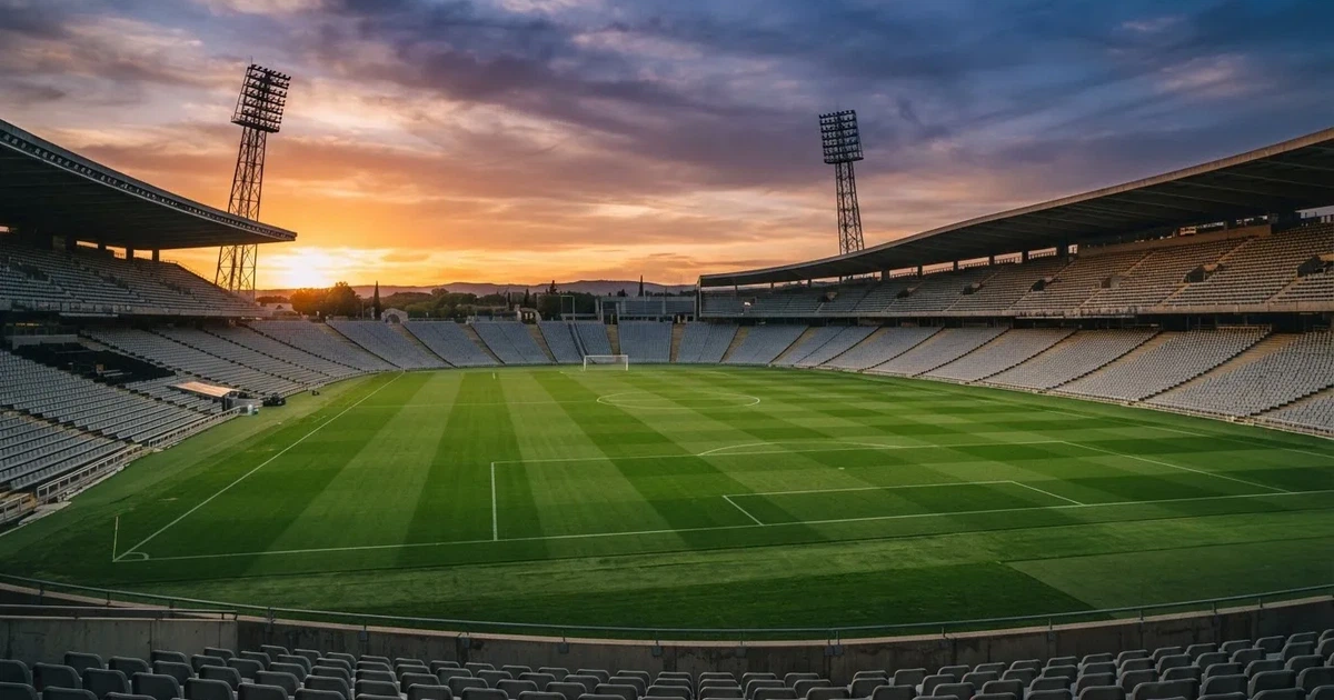 Un estadio de fútbol vacío con torres de iluminación al atardecer