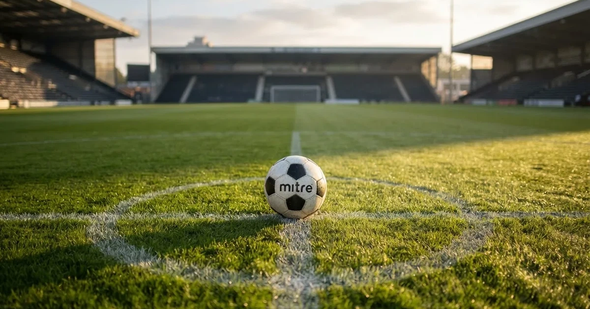 Un balón en el punto central de un campo de césped a la luz de la mañana