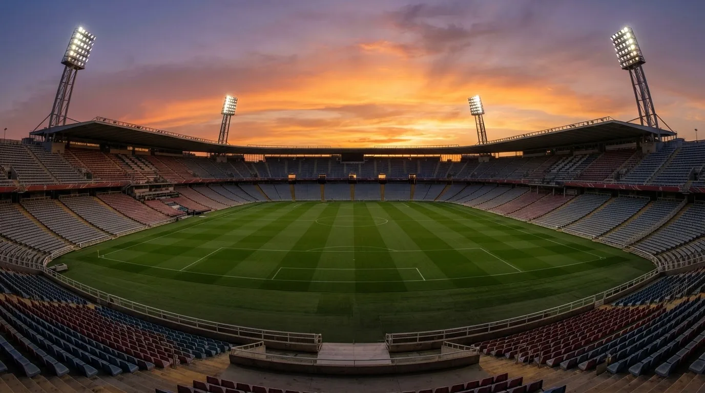 Un estadio de fútbol vacío con torres de iluminación al atardecer