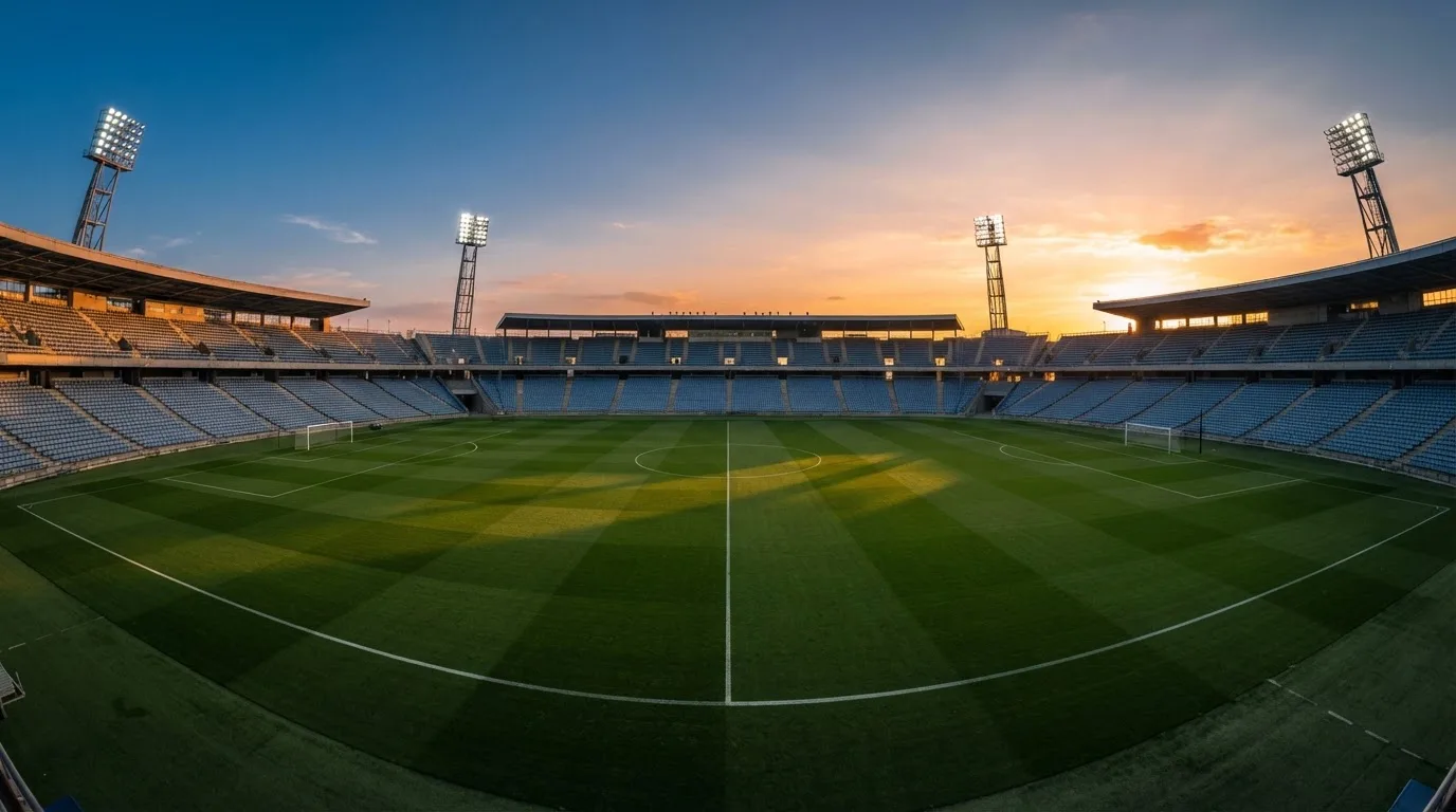 Un estadio de fútbol vacío con torres de iluminación al atardecer
